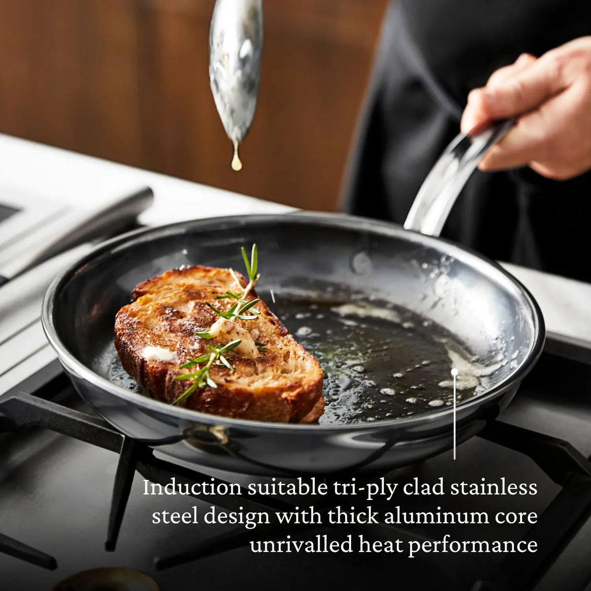 A person cooks a herb-topped bread slice in a NanoBond 18-Piece Titanium Cookware Set frying pan on the stove; text below highlights its tri-ply clad design, exceptional heat performance, and premium quality.