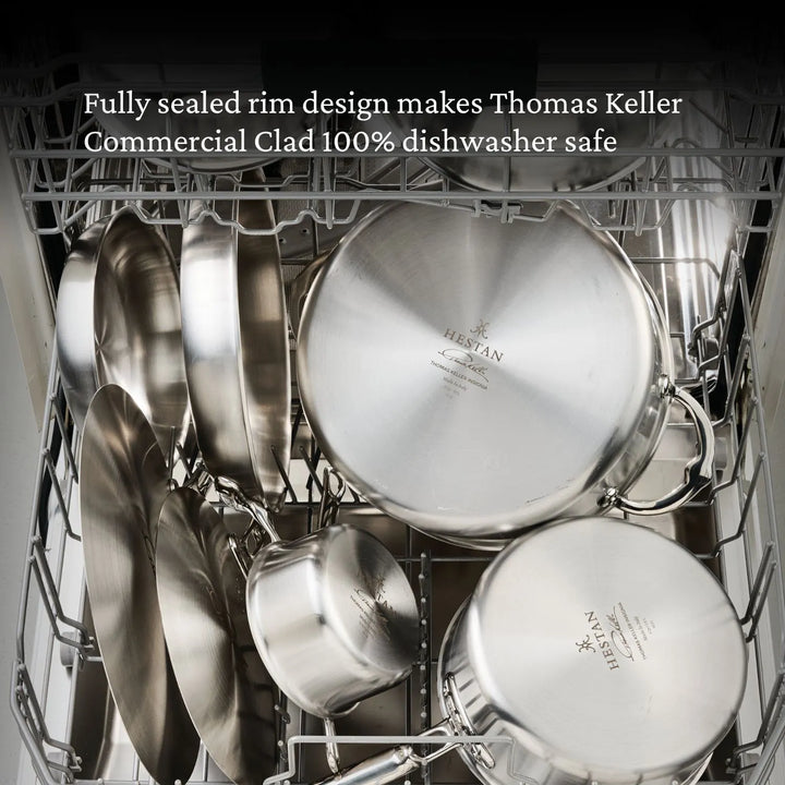 Open dishwasher reveals Thomas Keller Commercial Clad Stainless Steel 11-Piece Cookware Set—pots, pans, and lids. Highlighted text notes their fully sealed rims make them 100% dishwasher safe.