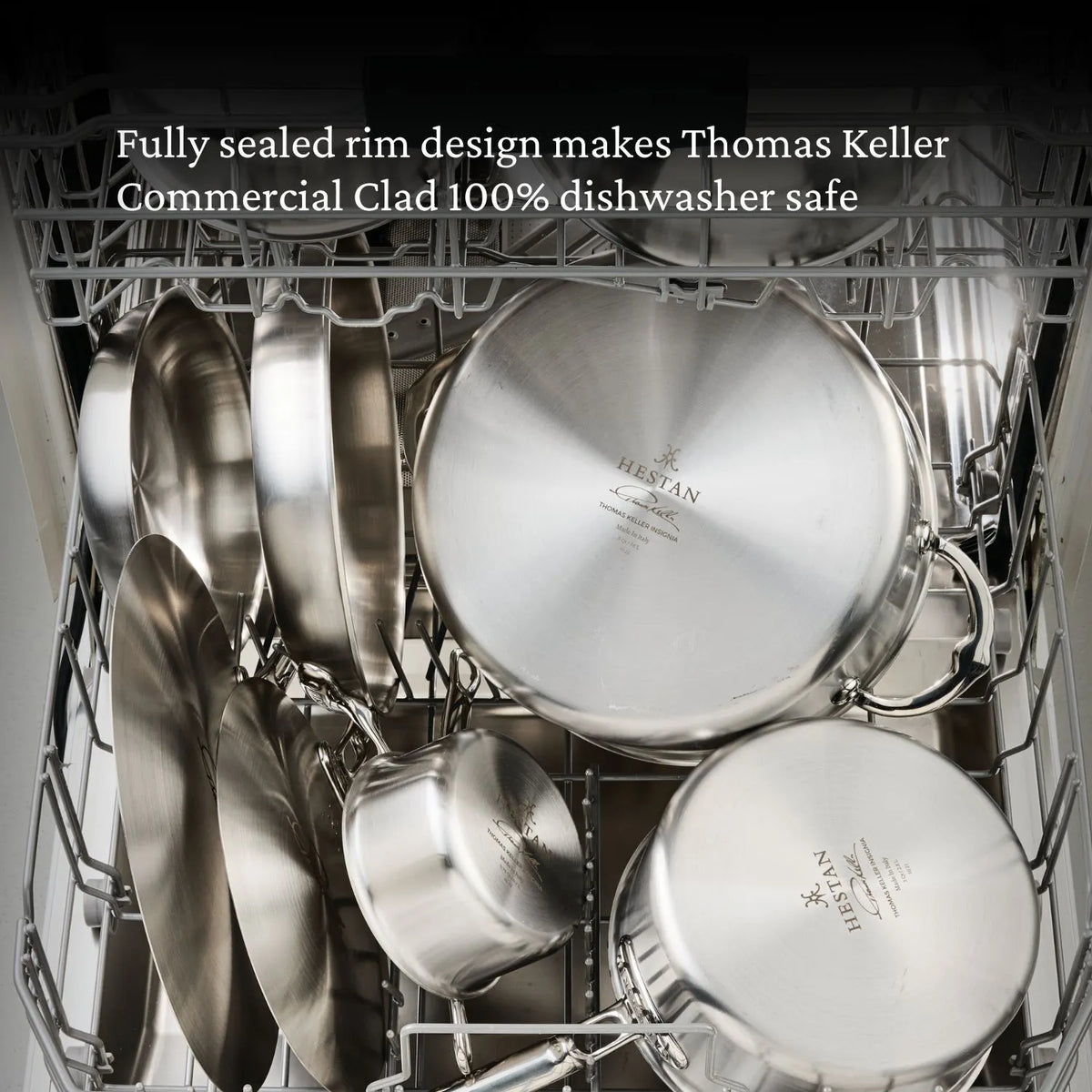 Open dishwasher reveals Thomas Keller Commercial Clad Stainless Steel 11-Piece Cookware Set—pots, pans, and lids. Highlighted text notes their fully sealed rims make them 100% dishwasher safe.